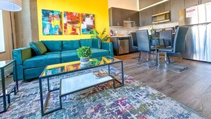 Una sala de estar moderna con un sofá azul verdoso, una mesa de centro y una alfombra colorida.