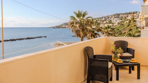 A balcony with wicker furniture, a small table, and a vase with flowers. - Casa Mare Torre San Carlo (Palma di Montechiaro)