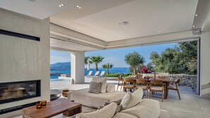 Een moderne woonkamer met een open haard, comfortabele zithoek en uitzicht op zee.