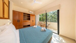 A bedroom with a bed, a wardrobe, a balcony with a table and chairs, and a view of greenery. - Lux 1 BR w/ Pool in Tulum Jungle @ Paraiso (Tulum)