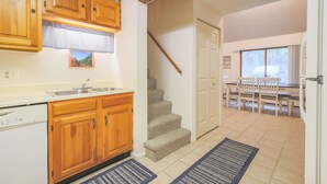 Eine Küche mit Holzausstattung, Geschirrspüler, Spüle und einer Treppe zu einem Essbereich mit Tisch und Stühlen.