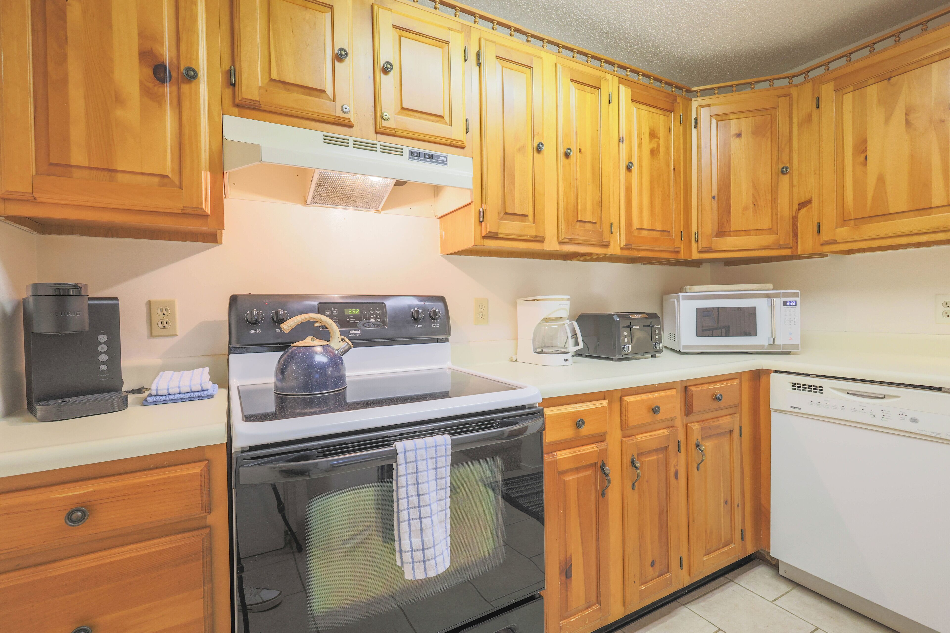 A kitchen with wooden cabinets, a stove, a microwave, and a dishwasher.