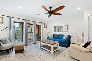 Relax in this stylish living room with a sofa set, coffee table, and framed artwork, leading out to an outdoor area.