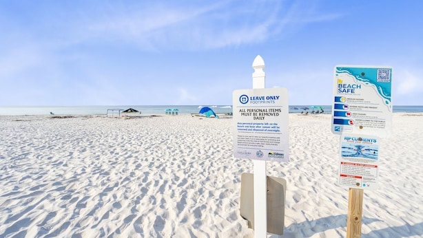 A beach with signs indicating 'Leave Only Footprints' and 'Beach Safe' guidelines. - Laguna Bella B5 | Pool View (Gulf Shores)
