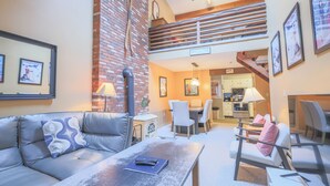 A living room with a sofa, coffee table, and a staircase leading to an upper level. - Official Seasons RMC Condo 09G - 2 bedrooms + loft - sleeps 10 - No Fees (Bartlett)