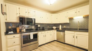 A kitchen with white cabinets, a microwave, a stove, and a sink. - Official Seasons RMC Condo 09G - 2 bedrooms + loft - sleeps 10 - No Fees (Bartlett)