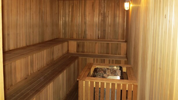 A wooden sauna with benches and a stone basin. - Official Seasons RMC Condo 09G - 2 bedrooms + loft - sleeps 10 - No Fees (Bartlett)