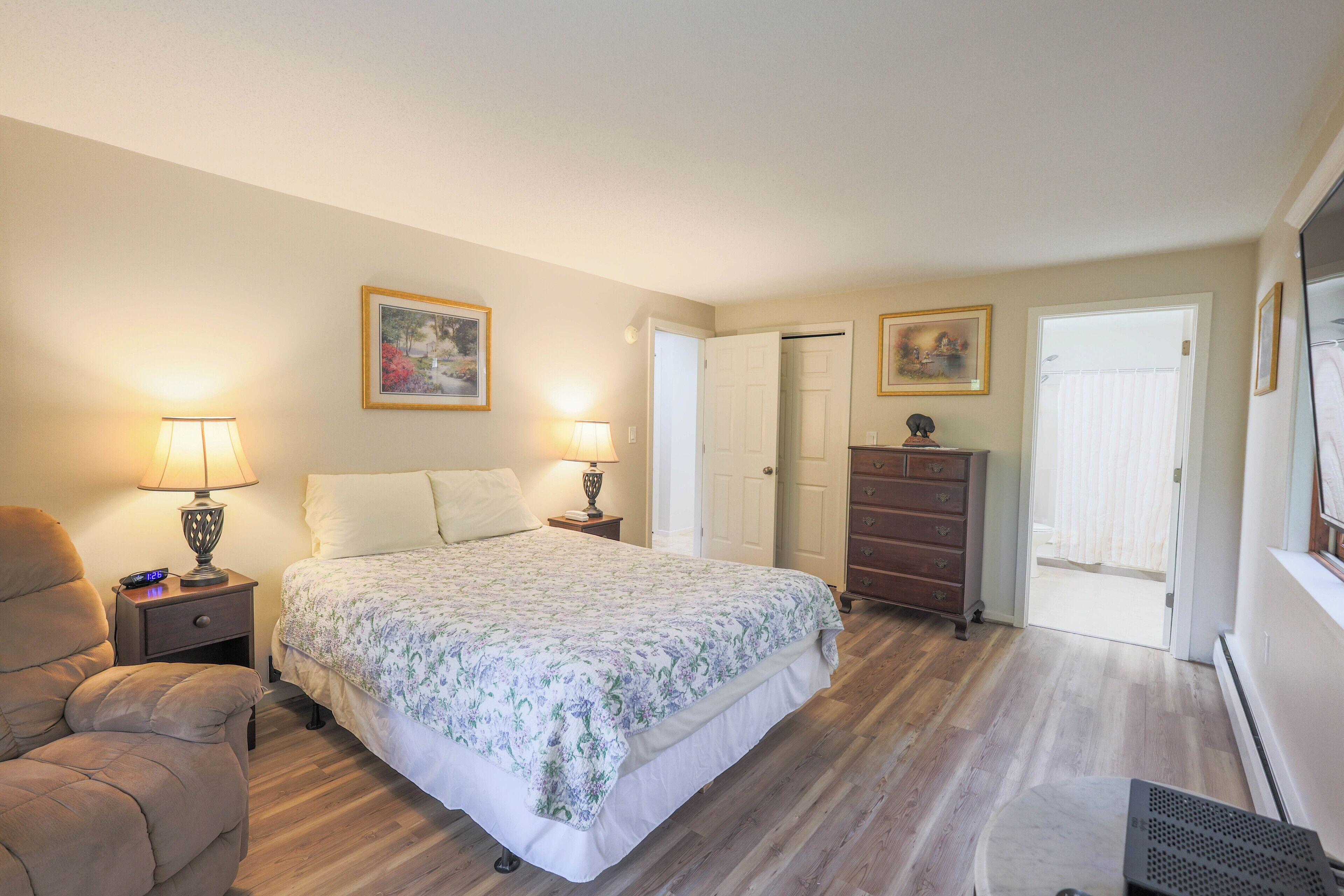 A bedroom with a bed, two bedside lamps, a dresser, and a chair.