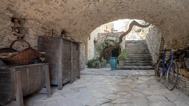 An interior with stone walls, a wooden bench, a wicker basket, a blue bicycle, and a staircase leading to an upper level. - 3-star gîte rental at the foot of the Cévennes in a beautiful old farmhouse, sleeps 12. (Saint-André-de-Buèges)
