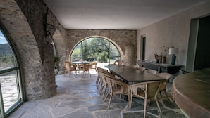 A stone-walled room with a large arched window, wicker furniture, and a stone floor. - 3-star gîte rental at the foot of the Cévennes in a beautiful old farmhouse, sleeps 12. (Saint-André-de-Buèges)