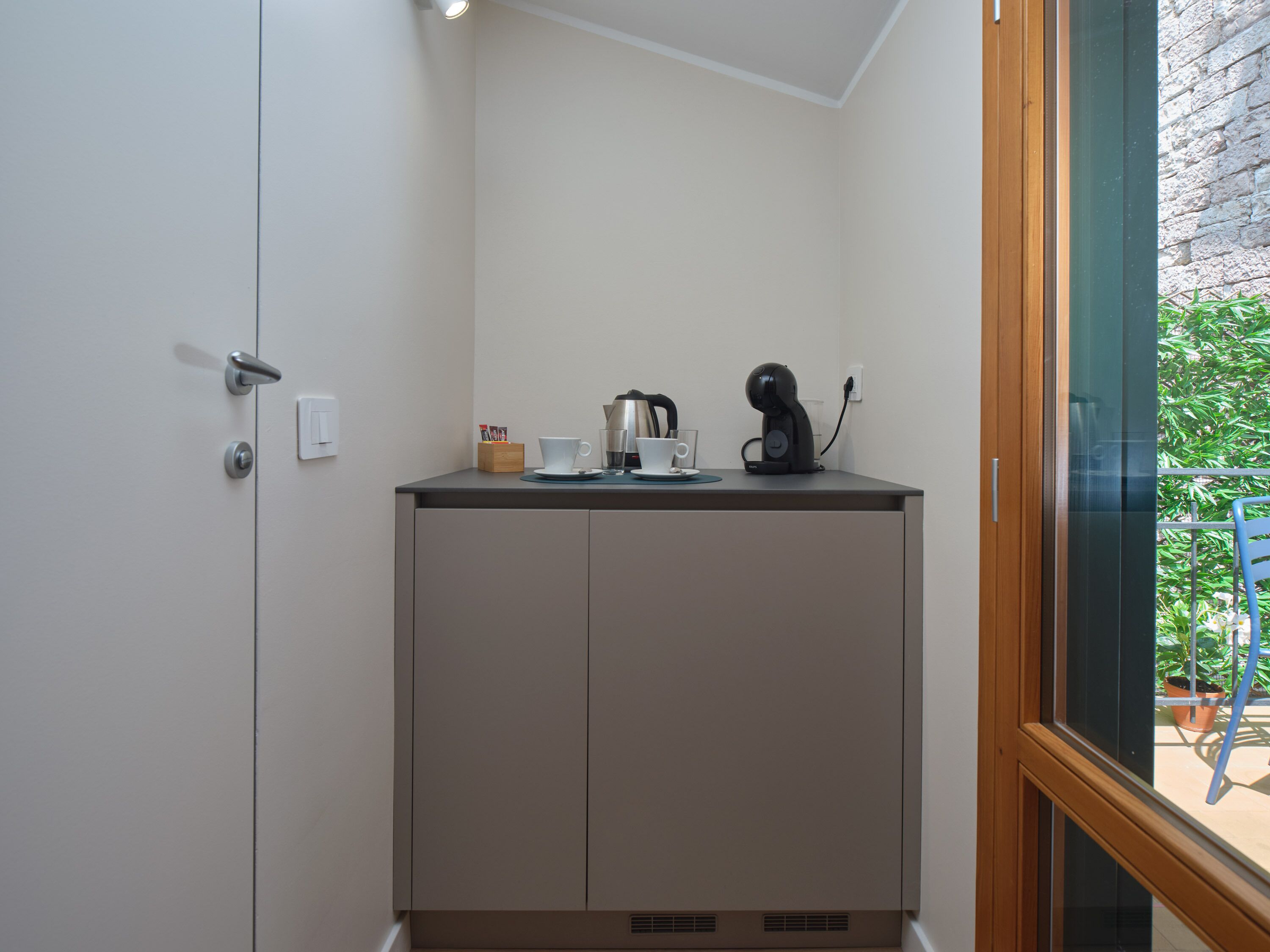 A kitchenette with a coffee maker, cup, and box of tissues.
