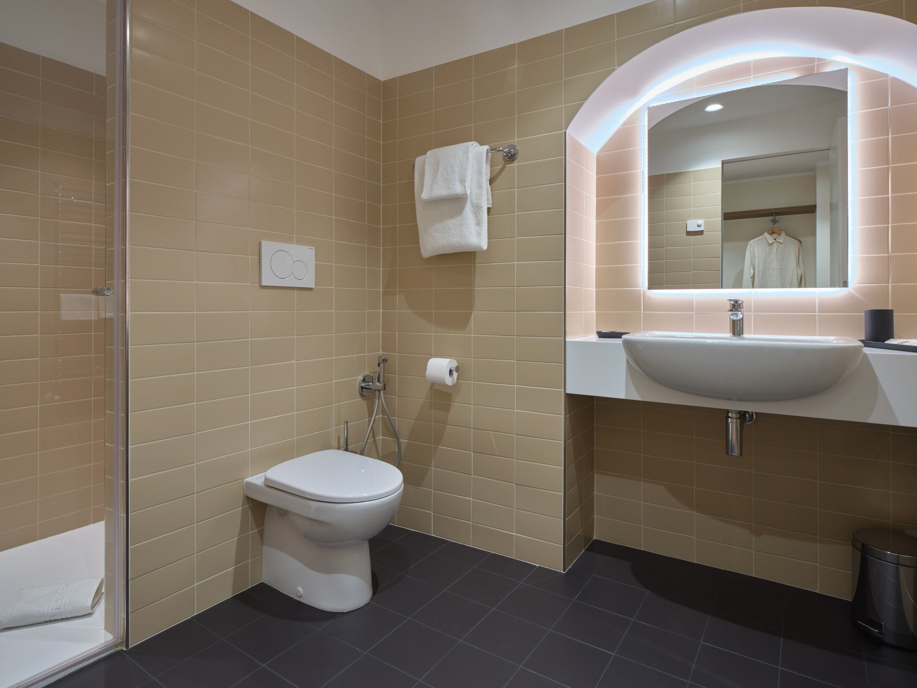 A modern bathroom with a toilet, shower, and sink.