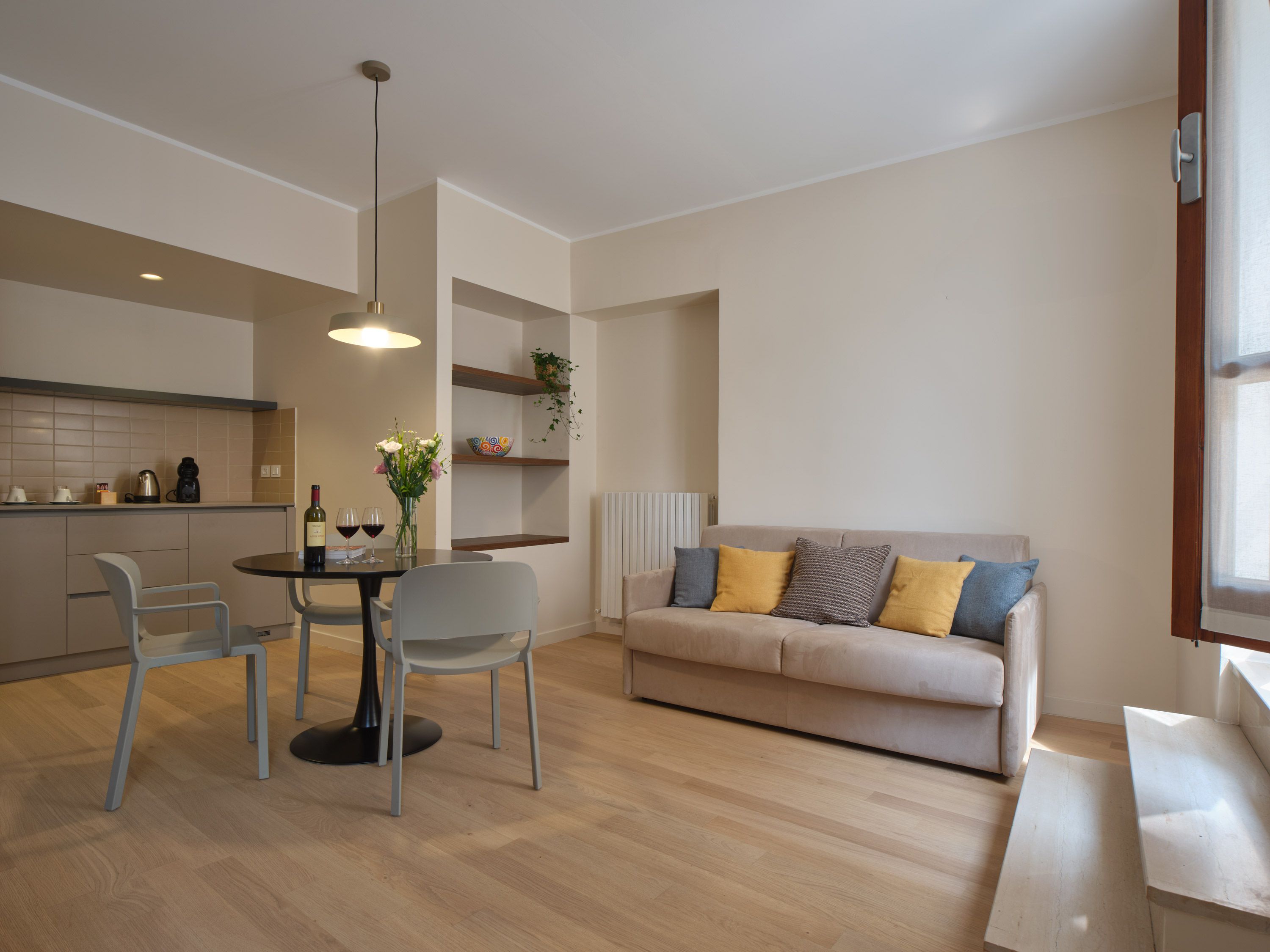 Un espacio habitable moderno con comedor, sofá y cocina al fondo.