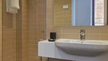 A modern bathroom with a glass shower enclosure, a white sink, and a mirror above it.