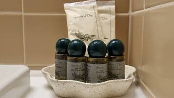 A white ceramic dish containing six bottles of Goccia d'Oro shampoo, with a white towel in the background.