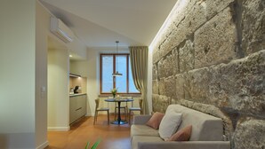Un salon moderne avec un mur d’accent en pierre, un coin repas avec une table ronde et une cuisine en arrière-plan.
