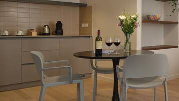 A modern kitchen with a dining area, featuring a round table with chairs, a wine bottle, and glasses.