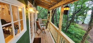 Une terrasse en bois avec une chaise, un paillasson et une vue sur une forêt.