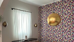 A dining area with a round table, bench seating, and a colorful geometric-patterned wall. - Renovated & Authentic San Juan 1-Bedroom APT w/ Caribbean Views (San Juan)