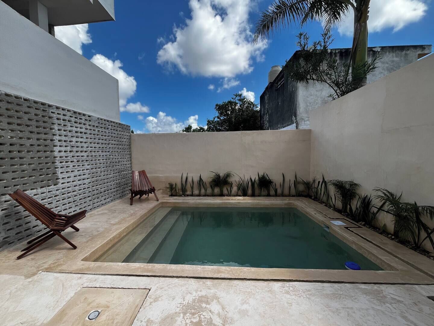 Une piscine rectangulaire dotée d’une terrasse en bois et d’une paroi métallique percée de trous.
