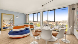 Ein modernes Wohnzimmer mit Essbereich, großen Fenstern und Blick auf die Stadt.