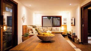 Ein modernes Wohnzimmer mit einem Holzes Esstisch, einer gemütlichen Couch und einem großen Fenster.