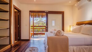 Ein Hotelzimmer mit einem Bett, Holzboden, einem kleinen Teppich und Blick auf einen Balkon mit Pflanzen.