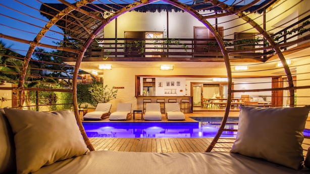 Ein Poolbereich mit Liegestühlen und einer Pergola aus Bambus.