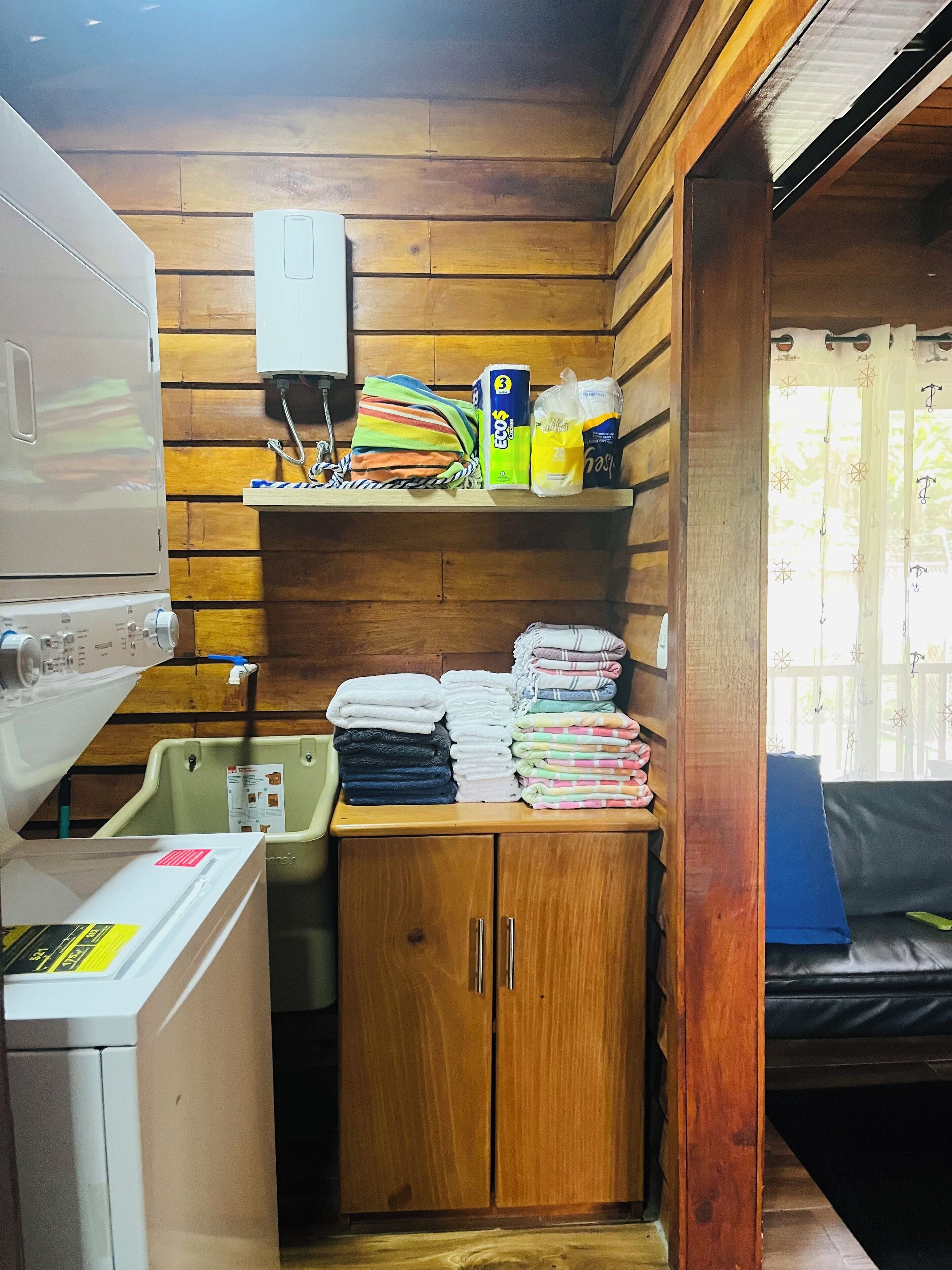 Une cuisine compacte avec des murs en bois, un lave-linge, un étendoir et un petit évier.