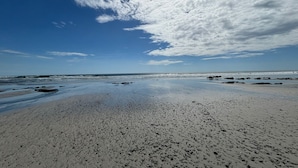 Ein Strand mit blauem Himmel und vereinzelten Wolken.