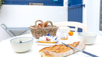 Une table avec une miche de pain, un couteau, un bol, un pot de beurre et un panier de pain.