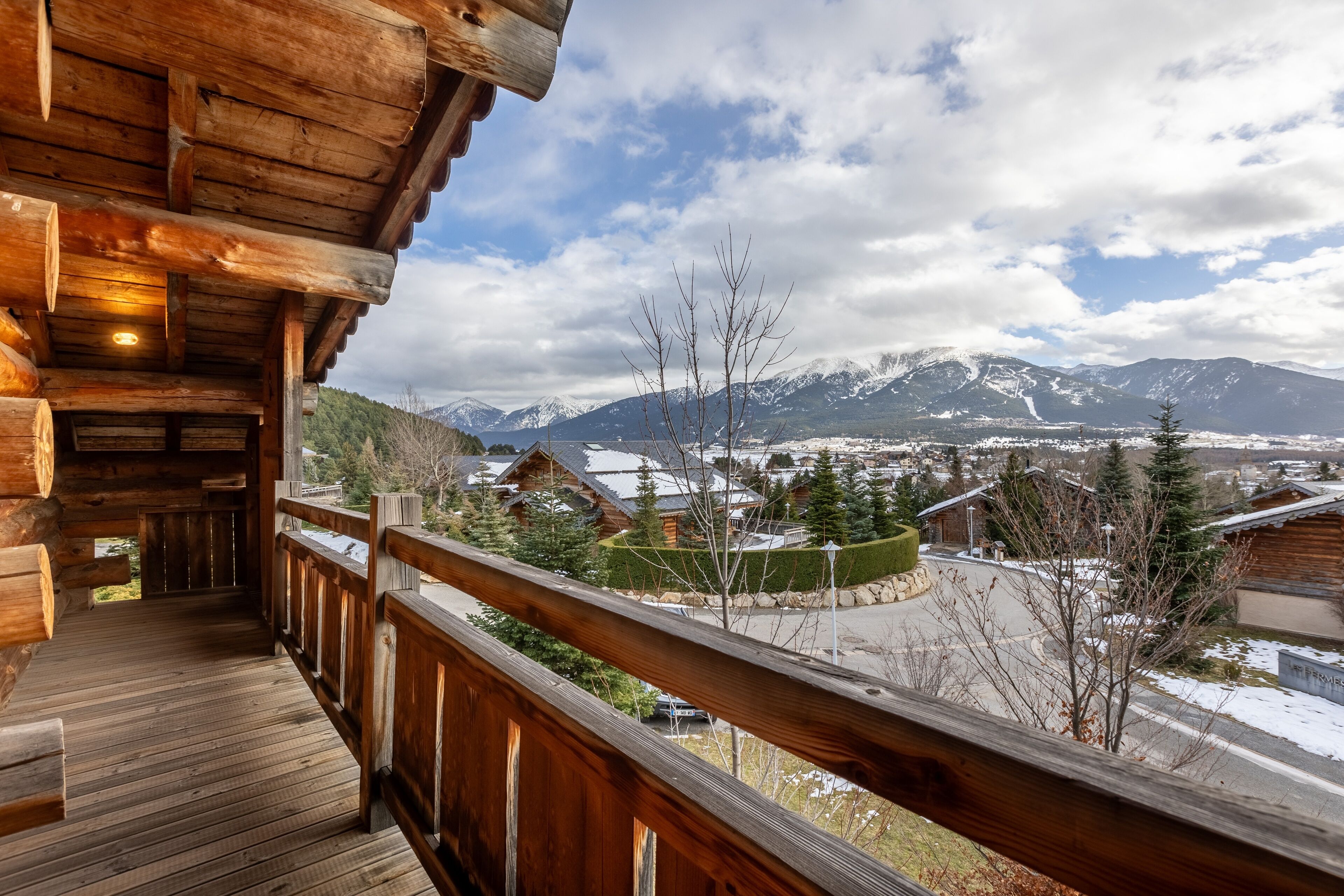 Une cabane en bois dotée d’un balcon donnant sur un paysage montagneux enneigé.