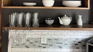 A kitchen with wooden shelves holding various dishes and glassware.
