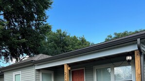 A single-story house with a porch, a number '2124' on the post, and a red door.