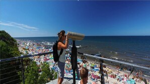 Un balcón con vista a una playa concurrida y al mar.
