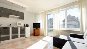 Un apartamento moderno con cocina, sala de estar con sofá, televisor y balcón con vistas a edificios.