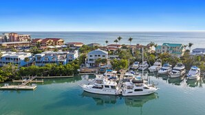 Un puerto deportivo con varias embarcaciones amarradas, rodeado de edificios residenciales y palmeras.