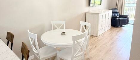 Un coin repas avec une table ronde et des chaises, un meuble blanc et un luminaire au plafond.