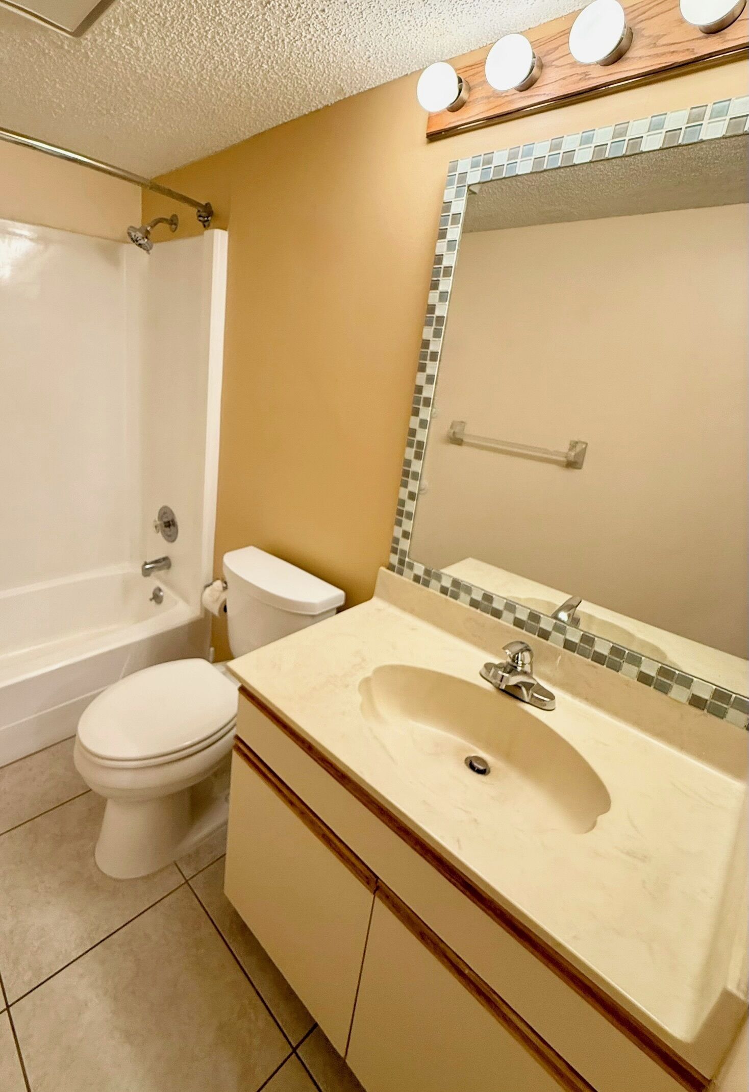 Un baño con bañera, inodoro, lavamanos y espejo.
