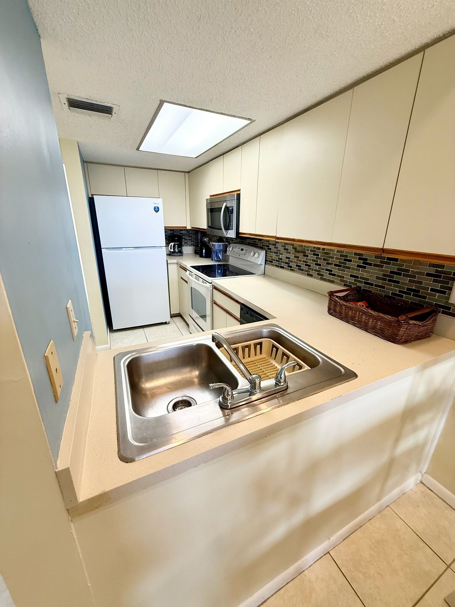 A compact kitchen with a built-in sink, a refrigerator, a microwave, and a stove.