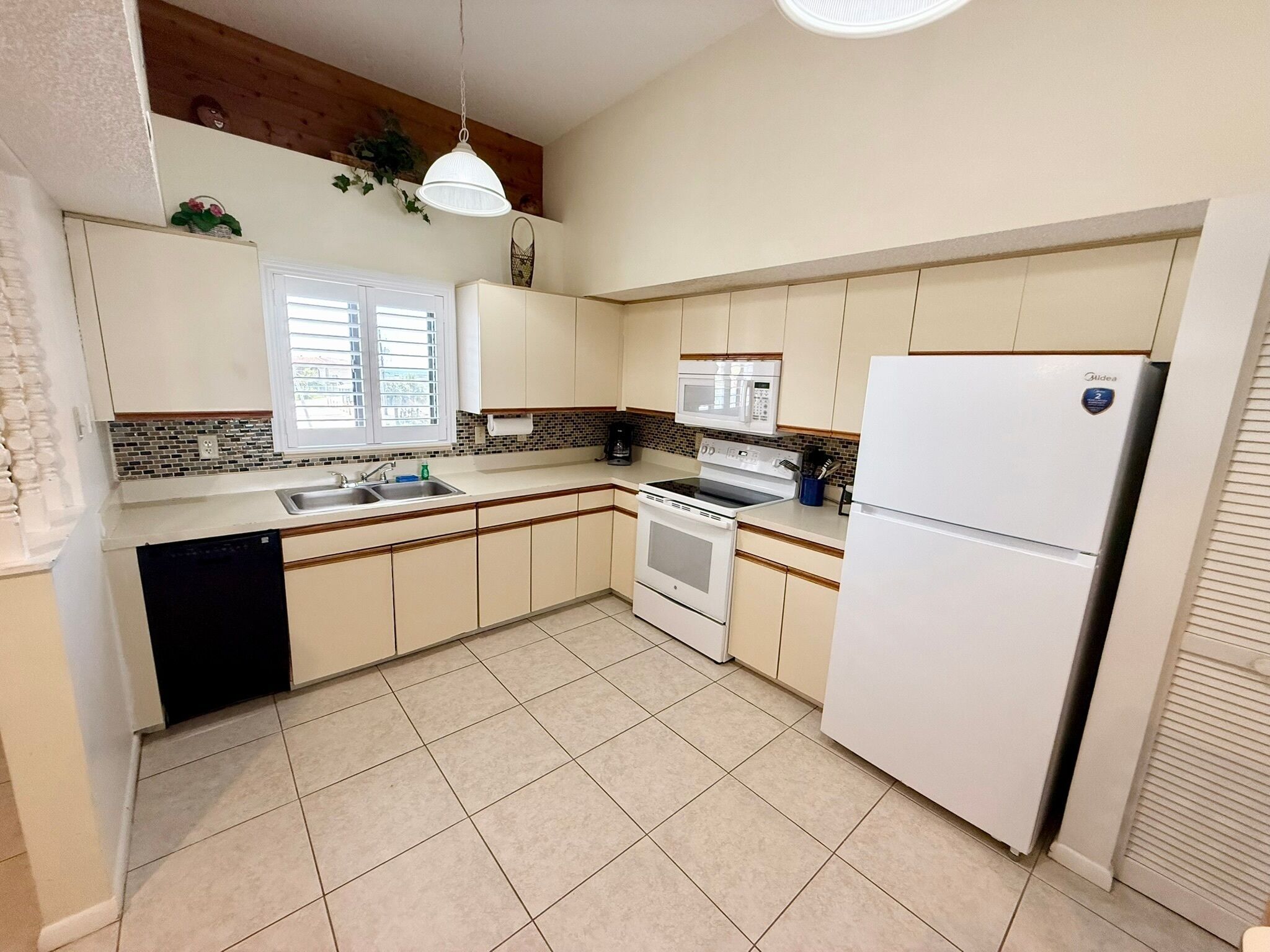 Una cocina con gabinetes blancos, un lavamanos doble, una estufa, un microondas y un refrigerador.