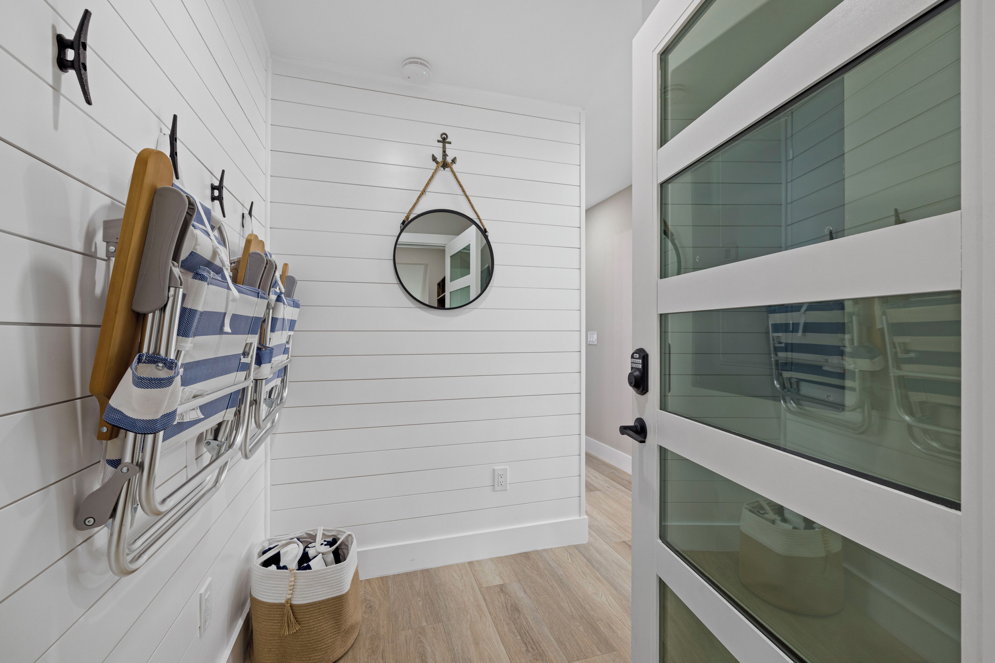 A hallway with a white door, a mirror, and a rack with towels and a wooden hanger.