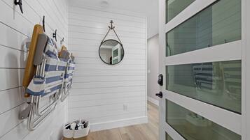 A hallway with a white door, a mirror, and a rack with towels and a wooden hanger.