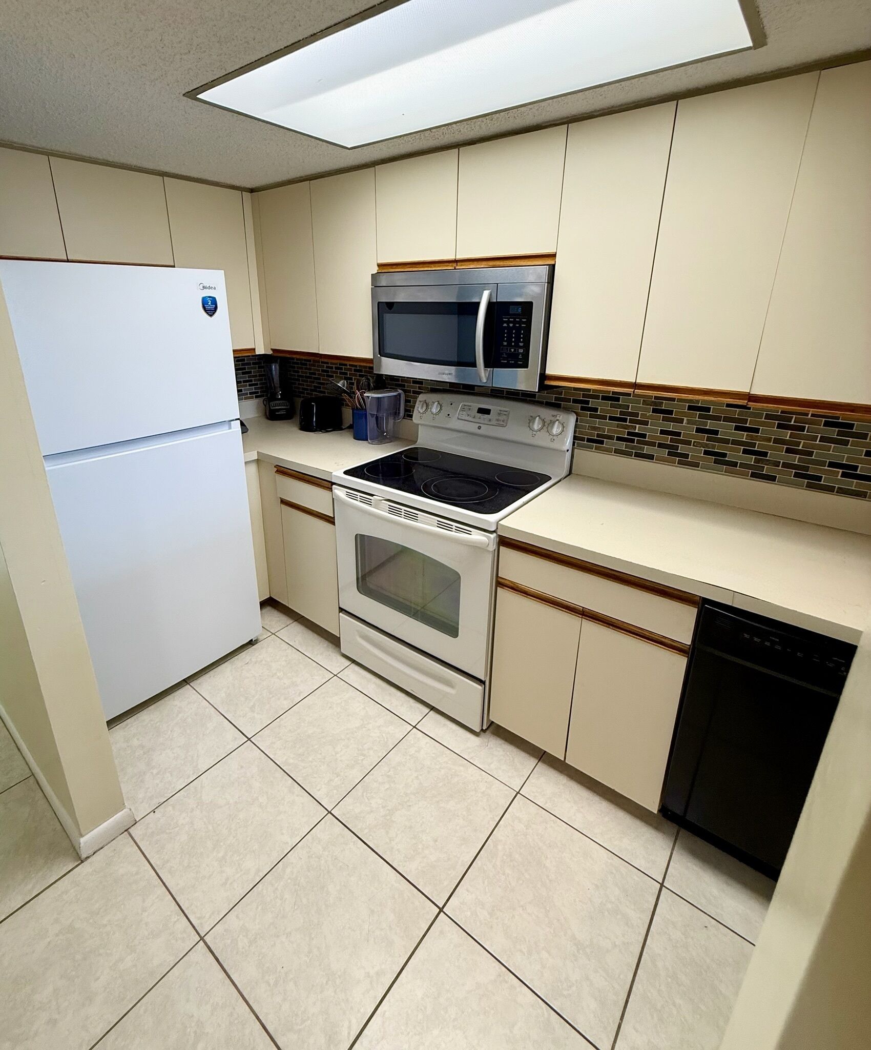 A compact kitchen with a refrigerator, microwave, stove, and dishwasher.