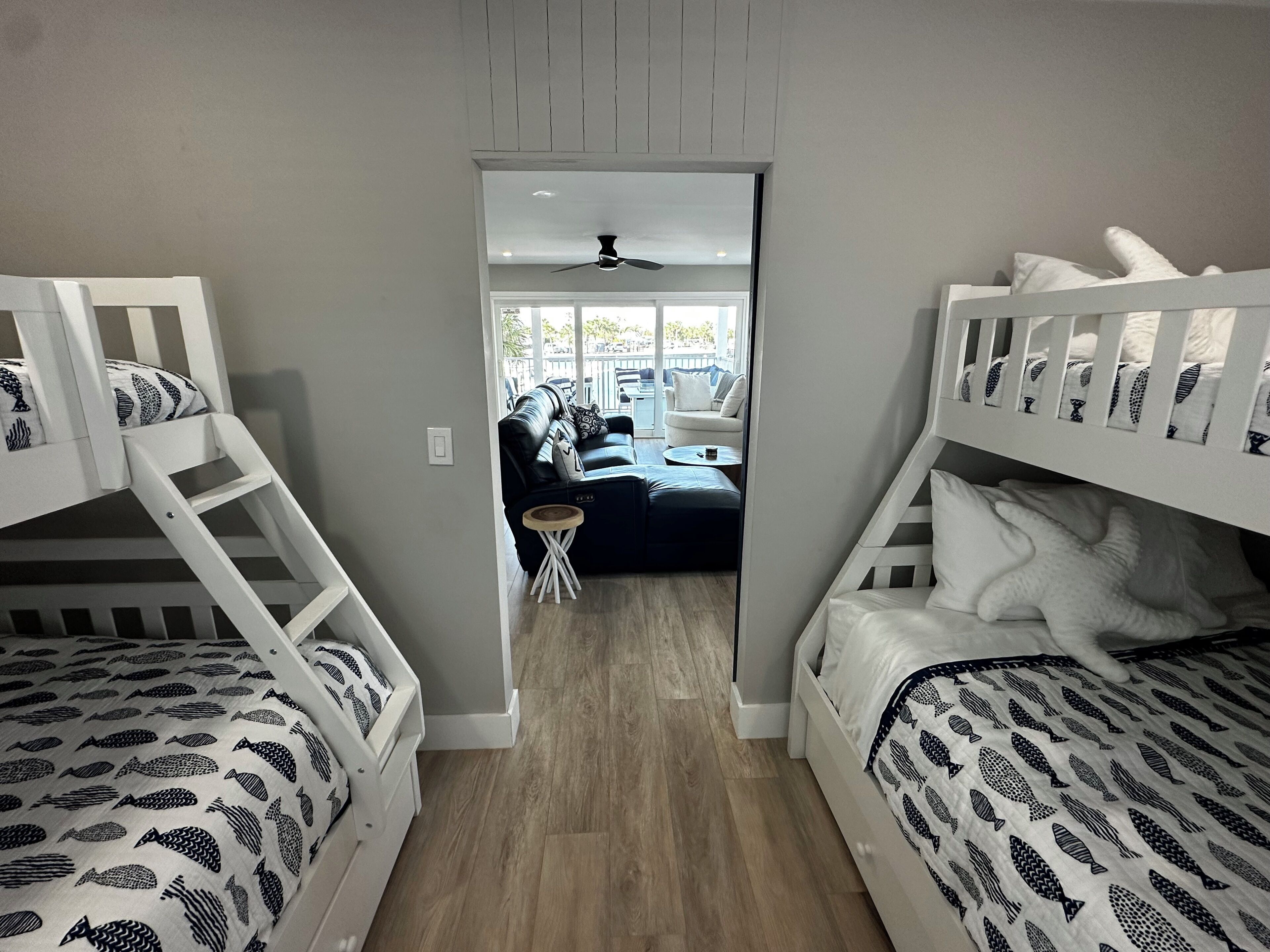 A room with bunk beds, a small round table, and a view of an outdoor seating area.