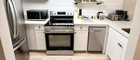 Una cocina compacta equipada con refrigerador, microondas, estufa y lavavajillas.