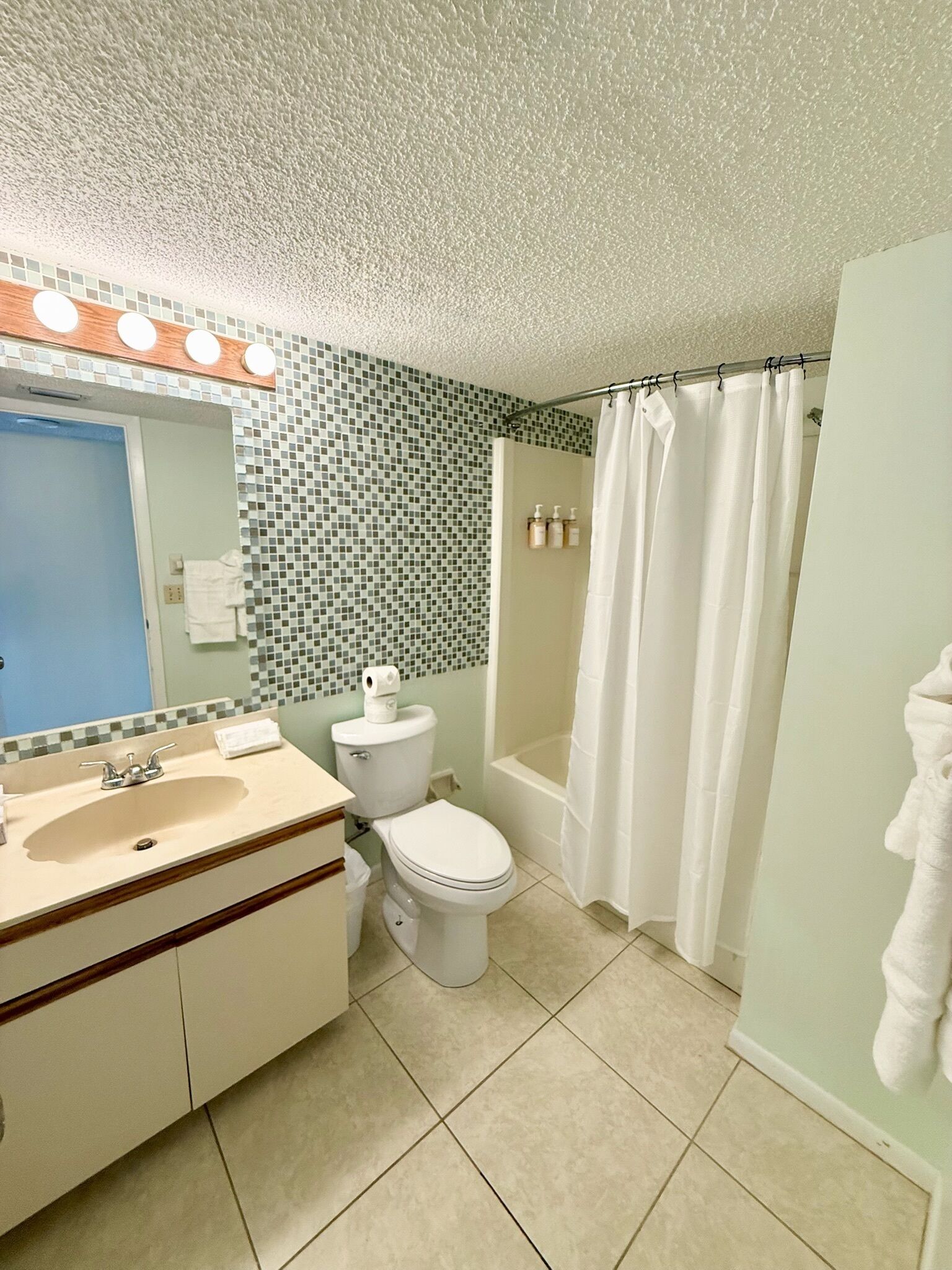 A bathroom with a sink, toilet, and shower curtain.