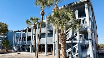 A multi-story building with a balcony on each floor, surrounded by palm trees.
