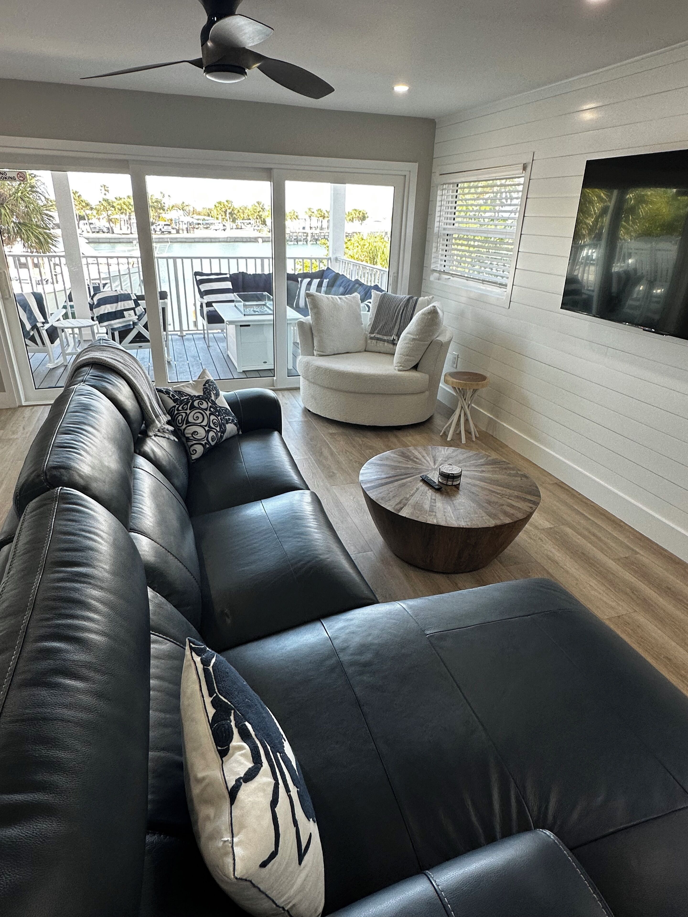 A modern living room with a black leather sofa, a round coffee table, and a white armchair.