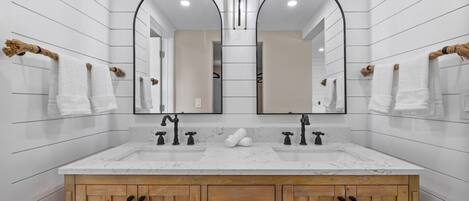 A bathroom with a white marble sink, wooden cabinets, and two large mirrors.